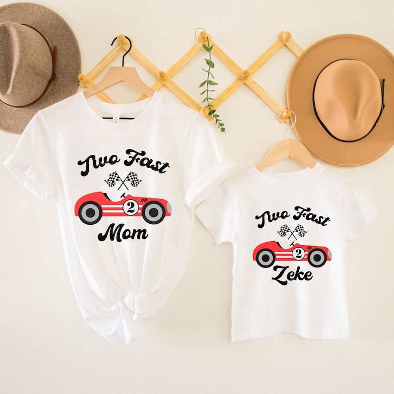 May include: Two white t-shirts with a red race car graphic and the text "Two Fast" and either "Mom" or "Zeke".