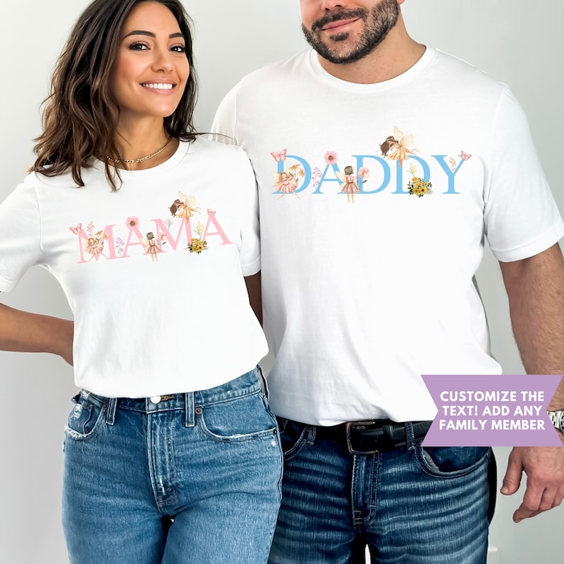 May include: Two white short-sleeved t-shirts featuring graphic designs. One shirt displays the pink text MAMA with fairy and floral illustrations. The other shirt displays the blue text DADDY with fairy and floral illustrations. A purple banner reads CUSTOMIZE THE TEXT! ADD ANY FAMILY MEMBER.