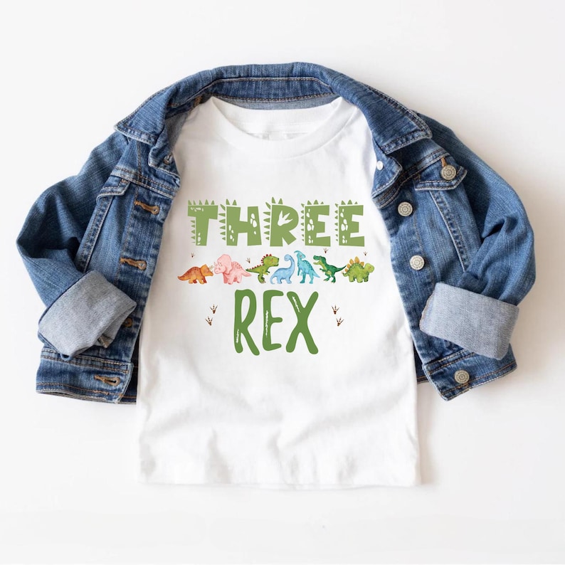 May include: White t-shirt with a green dinosaur graphic and the text "THREE REX".
