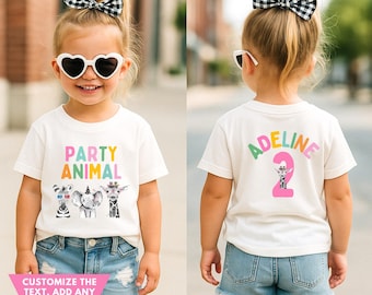 May include: A child wearing a white t-shirt with the words "PARTY ANIMAL" and animal graphics. The back of the shirt has the name "ADELINE" and the number "2". The child is wearing denim shorts, heart-shaped sunglasses, and a black and white bow.