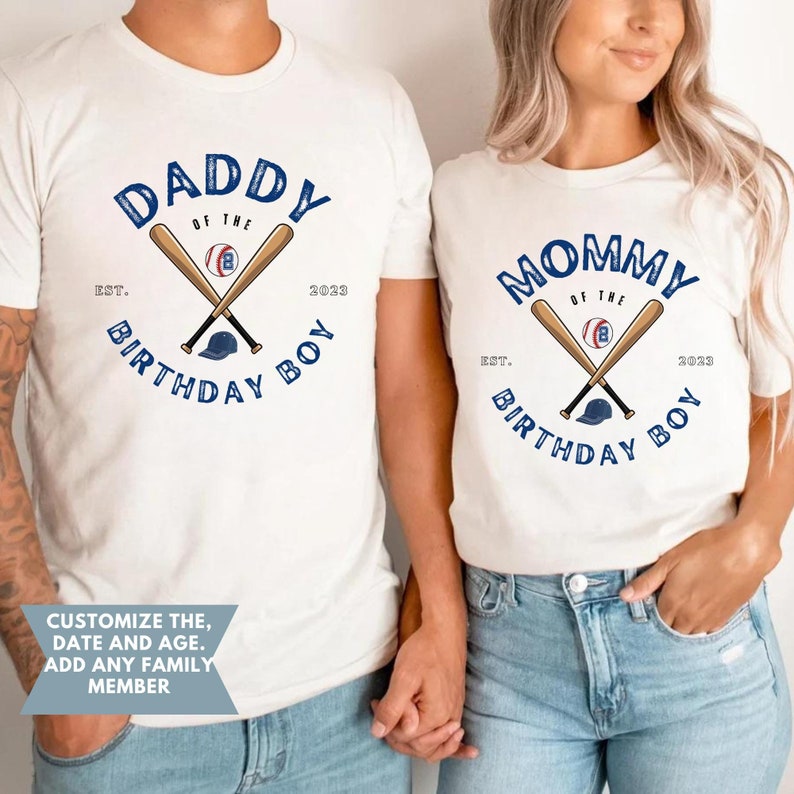 K&ouml;nnte beinhalten: Off-white T-Shirts mit Baseball-Motiven. Eines der Shirts tr&auml;gt die Aufschrift "DADDY of the BIRTHDAY BOY" mit gekreuzten Schl&auml;gern, einem Baseball und einer Kappe. Das andere Shirt tr&auml;gt die Aufschrift "MOMMY of the BIRTHDAY BOY".