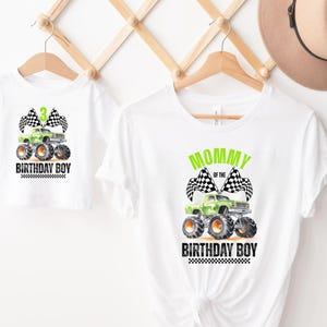 Puede incluir: Camisetas blancas con un dise&ntilde;o de monster truck. Una camiseta dice "3 BIRTHDAY BOY" con un monster truck verde y banderas a cuadros. La otra dice "MOMMY OF THE BIRTHDAY BOY". Ambas est&aacute;n en perchas de madera.