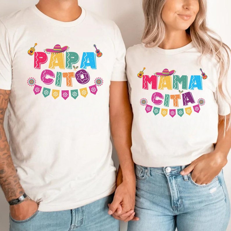 K&ouml;nnte beinhalten: Zwei wei&szlig;e T-Shirts mit buntem Text und Grafiken. Das erste Shirt sagt "Papa Cito" mit einem Sombrero und einer Gitarre. Das zweite Shirt sagt "Mama Cita" mit einem Sombrero und einer Gitarre.