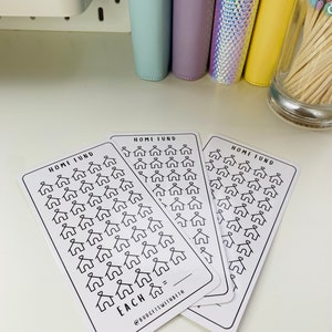May include: Three white cards with black outlines of houses on them. The cards are labeled "Home Fund" and have the text "Each =" at the bottom. The cards are stacked on top of each other.