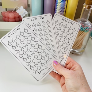 May include: Three white cards with black outlines of houses printed on them. Each card has the text "HOME FUND" at the top and the text "EACH" at the bottom. The cards are held in a hand.