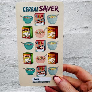 May include: A beige card with the words "CEREAL SAVER" at the top. The card features illustrations of cereal boxes and bowls of cereal. The text "EACH = @BUDGETSWITHBETH" is at the bottom. The card is held by a person.