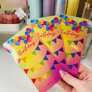 May include: Three colourful cards with a watercolour design of balloons and flags. The cards say "birthdays" in a white script font. The cards have a gradient background that goes from yellow to orange to pink. The bottom card has the text "@budgetswithbeth" in white.