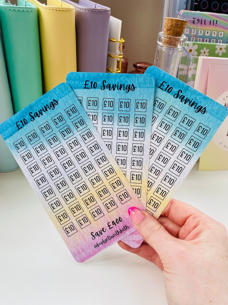 May include: Four colorful cards with a watercolor background and the text "&pound;10 Savings" printed on each card. Each card has a grid of 40 squares with the text "&pound;10" printed in each square. The cards are stacked on top of each other and the bottom card has the text "Save &pound;400" and "@budgetswithbeth" printed on it.