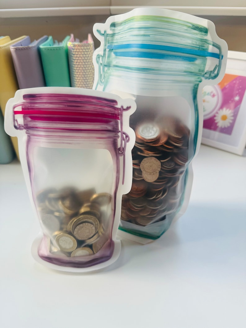 May include: Two clear plastic bags shaped like jars, filled with coins. The bag on the left has a pink lid and the bag on the right has a blue lid.