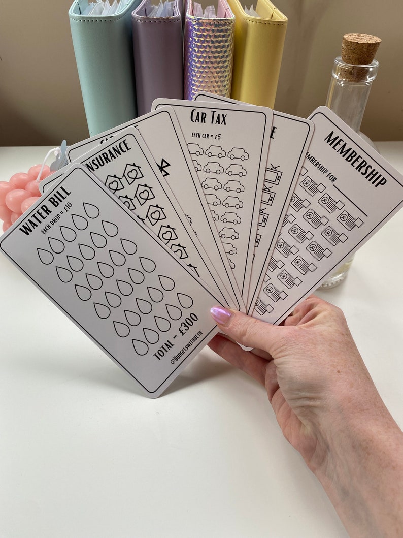 May include: A set of six white cards with black outlines and text. The cards are for tracking expenses and include categories like water bill, insurance, car tax, and membership. Each card has a different design and includes a total amount.
