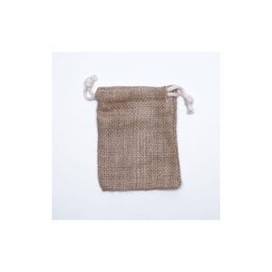 Puede incluir: Una pequeña bolsa rectangular de yute con cierre de cordón. La bolsa es de color marrón natural y tiene una textura tejida. El cordón es de un cordón blanco retorcido.