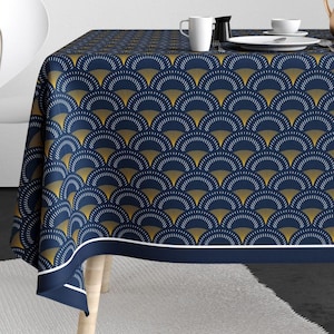 Könnte beinhalten: Eine marineblaue Tischdecke mit einem geometrischen Muster aus goldenen und weißen Bögen. Die Tischdecke hat einen weißen Rand und einen marineblauen Saum.