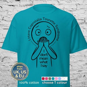 May include: Teal-colored t-shirt with a black graphic of a person covering their mouth, with the text "I have Coprolalia Tourette Syndrome. I don't mean what I say." The shirt is made of 100% cotton.