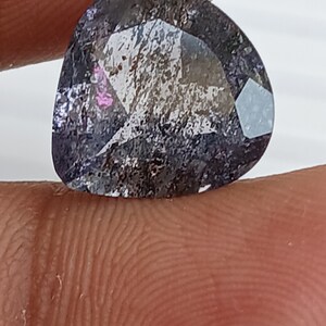 May include: A faceted, dark purple gemstone with a hint of pink and silver flecks. The gemstone is cut in a heart shape.