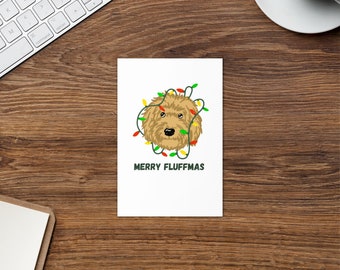 Może przedstawiać: Biała kartka z kreskówkową ilustracją brązowego psa, którego głowa otoczona jest kolorowymi światełkami choinkowymi. Pod psem widnieje napis "Merry Fluffmas".