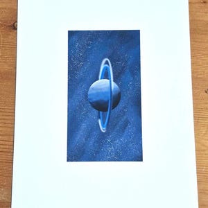 May include: A blue planet with a ring system against a dark blue starry background.
