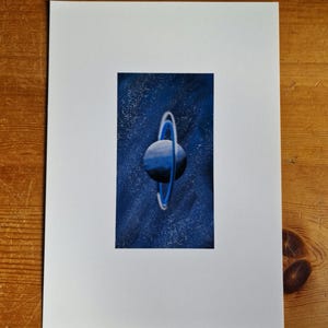 May include: A blue planet with a ring around it, set against a dark blue starry background.