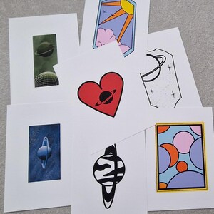 May include: Set of 7 printable art prints featuring a variety of colorful and abstract designs with a space theme. Each print features a planet with rings, a heart, a sun, and a variety of geometric shapes.