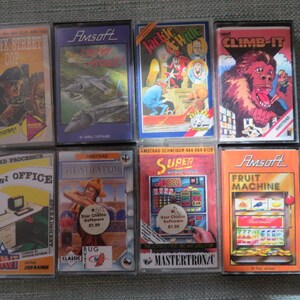 May include: Eight vintage video game cartridges for the Amstrad CPC computer. The cartridges are arranged in two rows of four. The cartridges are all different colors and have different titles, including "Bronx Street Cop", "Jackle & Hyde", "Climb-It", "Mini Office", "Gladiator", "Super", and "Fruit Machine".