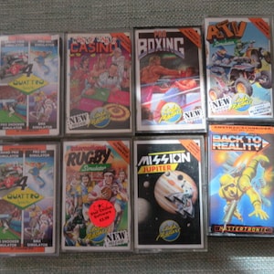 May include: A collection of eight vintage video game cartridges for the Amstrad CPC computer. The cartridges are in their original packaging and feature a variety of games, including "Pro Boxing", "ATV Simulator", "Mission Jupiter", "Back to Reality", "Rugby Simulator", "Grand Prix Quattro", "Pro Ski Simulator", and "Crazy Taxi Casino".