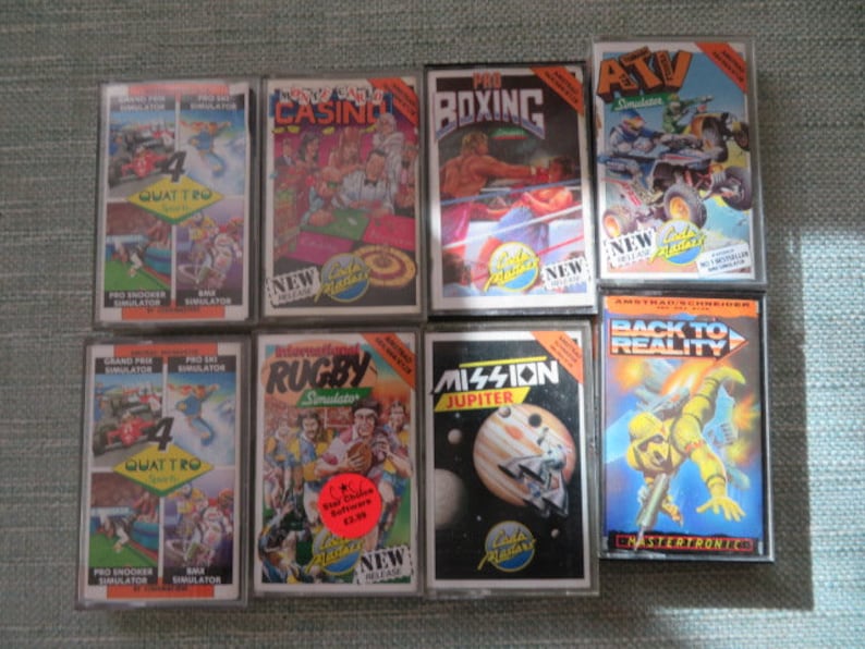 May include: A collection of eight vintage video game cartridges for the Amstrad CPC computer. The cartridges are in their original packaging and feature a variety of games, including "Pro Boxing", "ATV Simulator", "Mission Jupiter", "Back to Reality", "Rugby Simulator", "Grand Prix Quattro", "Pro Ski Simulator", and "Crazy Taxi Casino".