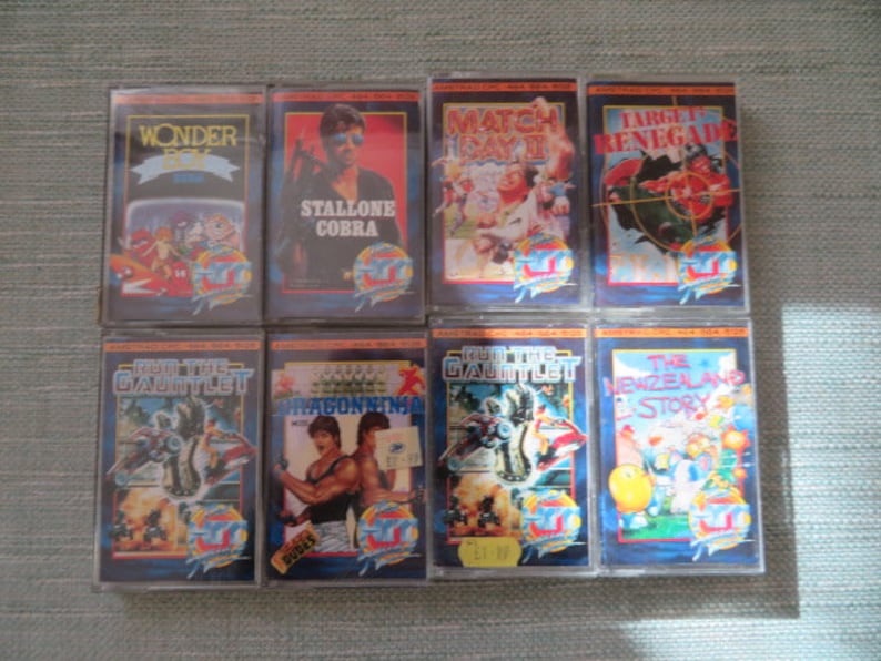 May include: Eight vintage video game cartridges with colorful labels and titles including "Wonder Boy", "Stallone Cobra", "Match Day II", "Target Renegade", "Run the Gauntlet", "Dragon Ninja", "Run the Gauntlet", and "The New Zealand Story".