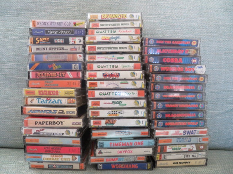 May include: A stack of vintage video game cartridges for the ZX Spectrum home computer. The cartridges are arranged in two columns, with titles such as "Bronx Street Cop", "Harrier Attack", "Super", "Mini Office", "Cobra", "Wonder Boy", "Tarzan", "Airwolf 2", "Paperboy", "Timeman One", "Skyfox", "Bump'n'Jump", and "Wordhang".
