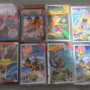 May include: A collection of 10 vintage video game cartridges for the Commodore 64. The cartridges are arranged in two rows of five. The cartridges are all in their original packaging and are in good condition. The cartridges include games such as Wolf, Dragon Ninja, Brainace, Pinball, Death Stalker, SAS Combat Simulator, Quattro Combat, MIG 29 Soviet Fighter, BMX Freestyle, and MIG 29 Soviet Fighter.