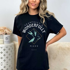 May include: Black t-shirt with a graphic of a bird in flight and the text "Fearfully & Wonderfully Made Psalm 139".