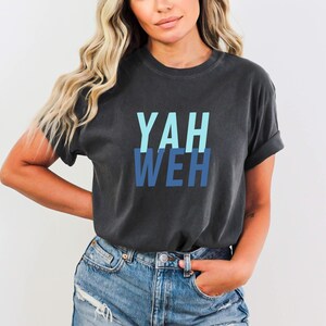 May include: A dark gray t-shirt with the word "YAHWEH" printed in blue and light blue letters.