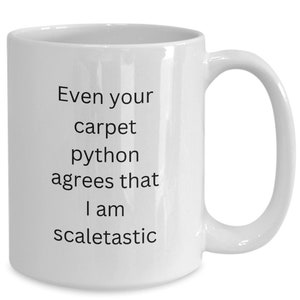 May include: White ceramic coffee mug with black text that reads "Even your carpet python agrees that I am scaletastic".