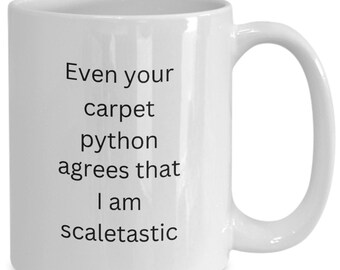 May include: White ceramic coffee mug with black text that reads "Even your carpet python agrees that I am scaletastic".
