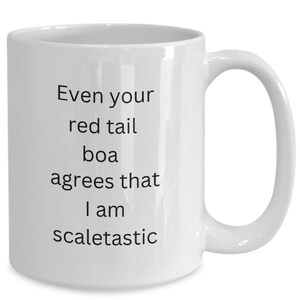May include: White ceramic coffee mug with black text that reads "Even your red tail boa agrees that I am scaletastic".