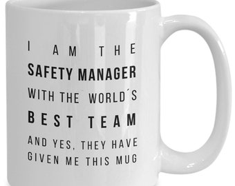 May include: White ceramic coffee mug with black text that reads "I am the Safety Manager with the world's best team and yes, they have given me this mug."