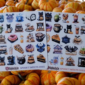 May include: Two sticker sheets with Halloween-themed illustrations of spooky sweets, cats, and haunted houses. The stickers are on a background of small orange pumpkins. The text "Spooky Sweets 2025" is printed on the stickers.