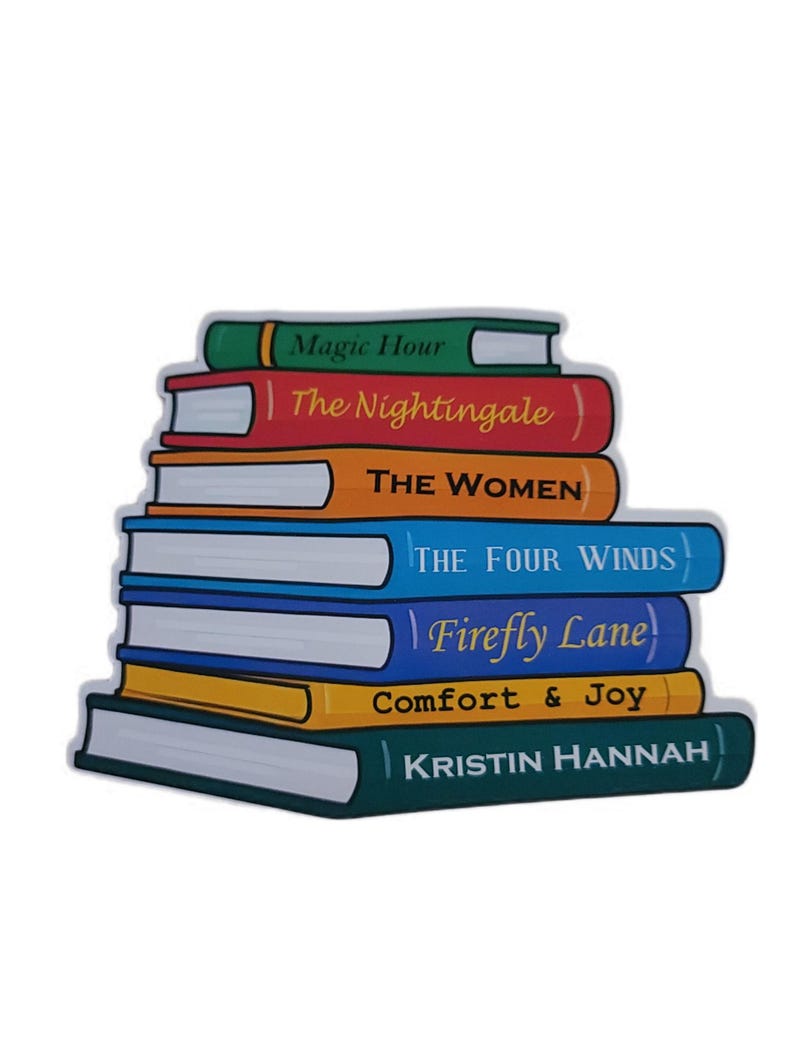 May include: A stack of seven books with colorful covers. Titles include "Magic Hour," "The Nightingale," "THE WOMEN," "THE FOUR WINDS," "Firefly Lane," "Comfort & Joy," and "KRISTIN HANNAH." The books are arranged in a neat pile.