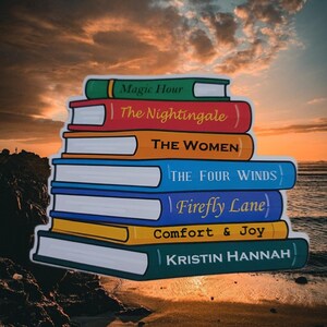 May include: A stack of colorful books with titles including "Magic Hour," "The Nightingale," and "The Women." The books are set against a sunset backdrop, with the author's name, Kristin Hannah, visible on the bottom book.
