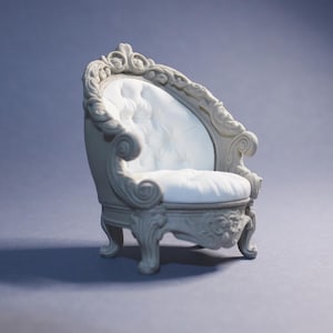 Puede incluir: Un sillón en miniatura, ornamentado, gris, con asiento y respaldo blancos acolchados. La silla presenta tallas detalladas y brazos curvos, mostrando un diseño clásico y elegante. La silla está sobre un fondo gris liso.