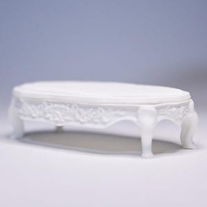 May include: A white ceramic mug with a black handle and the text "But First, Coffee" in a handwritten style. The mug is on a white surface. The mug is 4 inches tall.