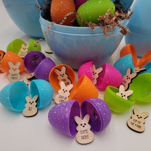 May include: A collection of colorful plastic Easter eggs with wooden bunny-shaped tokens inside. Each token has a different message, such as "Sweet Treat", "Game Night", and "Stay Up Late".