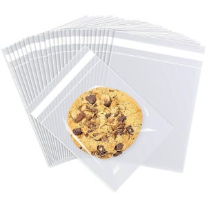 May include: A pile of clear cellophane bags, with a single chocolate chip cookie in one. The cookie is round, golden brown, and has visible chocolate chips. The bags are transparent and have a white, sealed top.