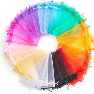 May include: A set of 20 colourful organza gift bags arranged in a circle. The bags are made of sheer fabric and have a drawstring closure. The colours include pink, purple, blue, green, yellow, orange, red, black, and white.