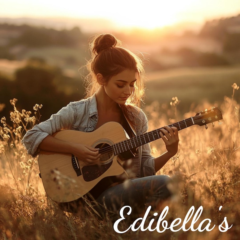 Op de afbeelding: Een vrouw zit in een veld met hoog gras en speelt een akoestische gitaar. De zon gaat achter haar onder en werpt een warme gloed over de sc&egrave;ne. De tekst "Edibella's" is zichtbaar in de rechterbenedenhoek van de afbeelding.