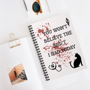 May include: A spiral-bound notebook with the text "YOU WON'T BELIEVE THE SHIFT I HAD TODAY" in black. The design includes red splatter, a veterinarian symbol, a paw print, a stethoscope, and a black cat silhouette.