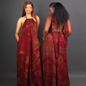 May include: Two floor-length, halter-neck dresses in a burgundy and brown tie-dye pattern. The dresses have a flowing, loose fit and pockets. One dress is viewed from the front, the other from the back, showcasing the open back design and tie detail.