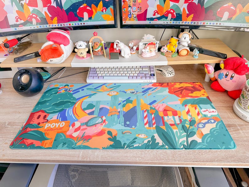 May include: A colorful desk setup featuring a large, rectangular mousepad with a whimsical illustration. The mousepad has a vibrant design with cartoonish elements, including a pig wearing goggles and the word "POYO". Various figurines and a keyboard are also visible.