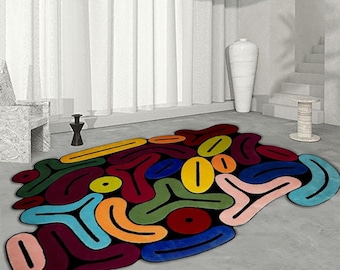 May include: Abstract area rug with a colorful design featuring various shapes and colors, including red, blue, green, yellow, and orange. The rug has a black outline around each shape.