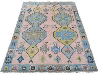 May include: A pink, blue, green, and yellow patterned rug with a geometric design. The rug has a fringed edge.