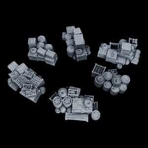Op de afbeelding: Zes stapels van miniatuurhouten kisten en vaten, geschilderd in lichtgrijs. De kisten en vaten zijn in willekeurige volgorde op elkaar gestapeld. De stapels zijn in een cirkel op een zwarte achtergrond gerangschikt.