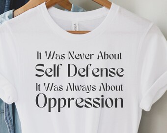May include: White t-shirt with black text that reads "It Was Never About Self Defense It Was Always About Oppression"